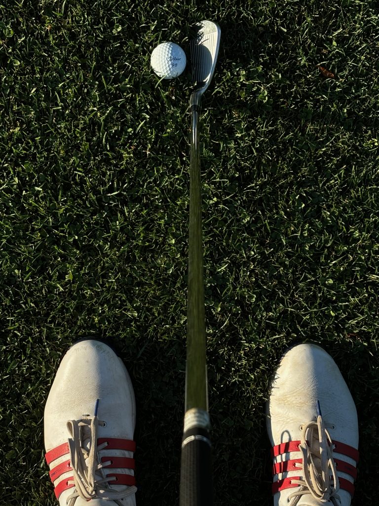 Pictured: Parker Bigornia's golf shoes while holding his golf club and addressing his golf ball